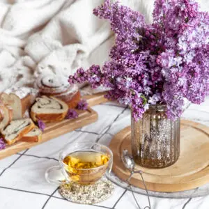 Breakfast or brunch in bed with pastries and tea. Lilac bouquet in a vase. Romance and holidays. Mother's and women's day.
